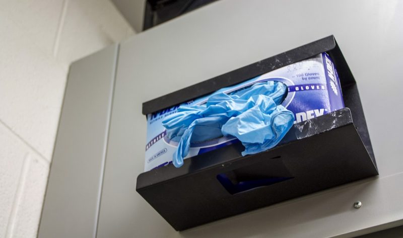 Box of blue gloves in container on wall