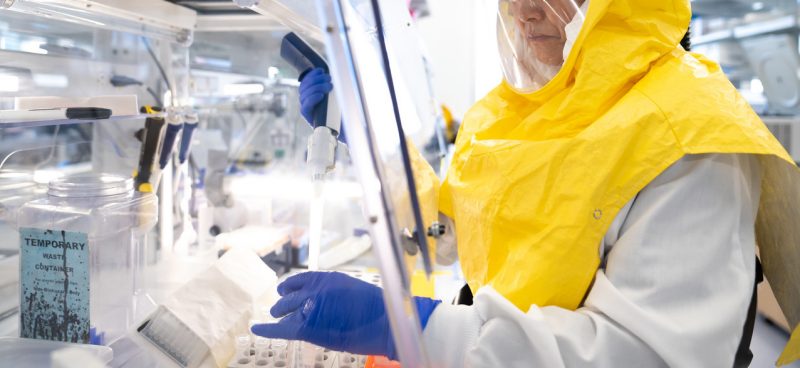 Person wearing yellow PPE standing in a lab