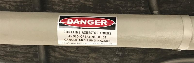 Pipe with a warning label that reads, "Warning, contains asbestos fibers, avoid creating dust, cancer and lung hazard
